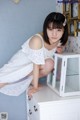 A woman in a white dress sitting on top of a dresser.